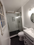 A remodeled bathroom featuring a Tile Redi shower pan, complete with a shower, toilet, and sink.