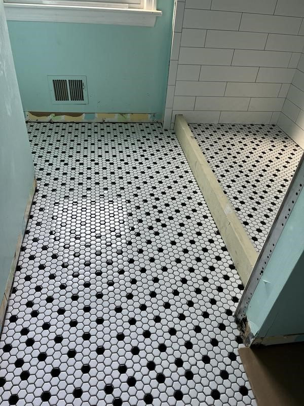 Modern bathroom features black and white tile flooring and Tile Redi shower pan.